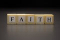 The word FAITH written on wooden cubes isolated on a black background