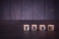 The word fake on wooden cubes, on a dark background, light wooden cubes signs, symbols signs Royalty Free Stock Photo