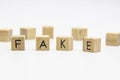 A word fake written on the wood cubes. Fake lettering made of wooden cubes isolated on white Royalty Free Stock Photo