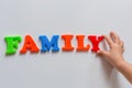 The word FAMILY is made of colored magnetic letters typed by a child`s hand.