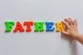 The word FATHER is made of colored magnetic letters typed by a child`s hand.