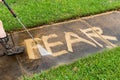 The word `FEAR` being erased with a pressure washer