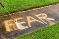 The word `FEAR` being erased with a pressure washer