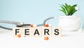 The word FEARS is written on wooden cubes near a stethoscope on a wooden background. Medical concept
