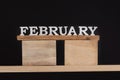Word February made of wooden letters on wooden stand. Black background. Front view Royalty Free Stock Photo