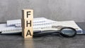 the word FHA is written on wooden cubes on a gray background. close-up of wooden elements, magnifying glass, paper Royalty Free Stock Photo