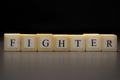 The word FIGHTER written on wooden cubes isolated on a black background Royalty Free Stock Photo