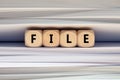 The word file on wooden cubes with paper and folder documents background. Filing, paperwork and documents overload in business Royalty Free Stock Photo