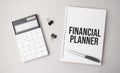 The word FINANCIAL PLANNER is written on a white background next to a pen ,calculator and reports. Business concept Royalty Free Stock Photo