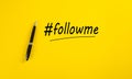 The word follow me or hashtag followme hand written with a black marker pen on yellow background Royalty Free Stock Photo