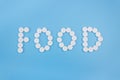 The word food made from medical pills on a blue background. Drug addiction and overdose concept Royalty Free Stock Photo