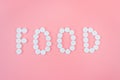 The word food made from medical pills on a pink background. Drug addiction and overdose concept Royalty Free Stock Photo