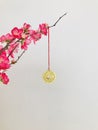 Golden copper coin, hanging on peach blossom branch, close up.