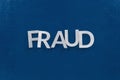 The word fraud laid with silver metal letters on classic blue painted board surface - wtih careless dodging order