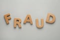 Word Fraud made of wooden letters on grey background, flat lay