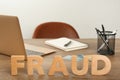 Word Fraud made of wooden letters near laptop and stationery on office desk