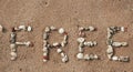 Word free made from sea shells on sandy beach Royalty Free Stock Photo