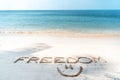 The word freedom written in the sand on a tropical beach, lifestyle vacation and travel design concept