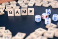 Word GAME with wooden letters on black Board with dice and letter in the circle Royalty Free Stock Photo