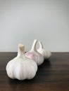 Three garlics on wood brown table, grey background. Vertical, copy space.