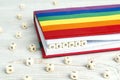 Word Gender written in wooden blocks in red notebook with rainbow LGBT flag on wooden table