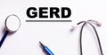 The word GERD is written on a white background near a stethoscope and a marker. Medical concept Royalty Free Stock Photo