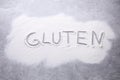Word Gluten written with flour on grey background, top view