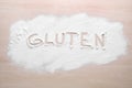 Word Gluten written with flour on wooden table, top view