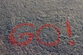 Word GO! written on the asphalt, ground. Red color of chalk.