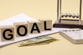 The word goal on wooden cubes, Newton`s cradle and American dollars Royalty Free Stock Photo