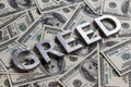 The word GREED laid with aluminium letters on the US dollar banknotes background - with selective focus Royalty Free Stock Photo