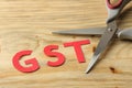 The word GST from paper letters and scissors on a natural wooden table. Taxes Royalty Free Stock Photo