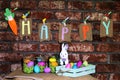 Word Happy on sackcloth tags hanging on a line with orange carrot, colorful Easter eggs in glass jars and white bunny rabbit