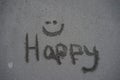 The word happy with a smilie face written in the sand Royalty Free Stock Photo