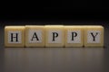 The word HAPPY written on wooden cubes isolated on a black background Royalty Free Stock Photo