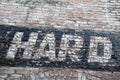 The word HARD is painted on an old brick wall. Ghost sign.