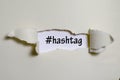 The word hashtag appearing behind torn paper