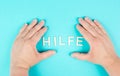 The word help stands in german language between the hands, giving support and charity Royalty Free Stock Photo