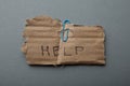 The word `help` written on cardboard, isolated on a gray background, poverty and despair.