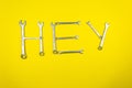 Word `Hey` laid out with wrenches on a yellow background