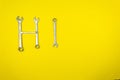 Word `Hi` laid out with wrenches on a yellow background