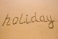 Word Holiday hand written in the wet sand. Close up sand texture on beach in summer Royalty Free Stock Photo