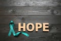 Word Hope made of letters and teal awareness ribbon on wooden background. Symbol of social and medical issues Royalty Free Stock Photo