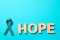 Word Hope of wooden letters and teal awareness ribbon on light blue background. Symbol of social and medical issues