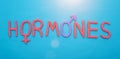 The word hormones from red plasticine on a blue background concept of all human hormones, inscription