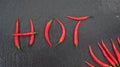 Word hot on a chalkboard. Red chili peppers. Black slate background. Hot seasoning concept Royalty Free Stock Photo