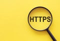 The word HTTPS is written on a magnifying glass on a yellow background