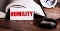 The word HUMILITY written on a white card near an open book, alarm clock and magnifying glass Royalty Free Stock Photo
