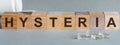 Word Hysteria. Hysteria text on wooden blocks. In front of a row of cubes are ampoules, in the background - white plastic