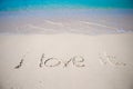 Word i love it handwritten on sandy beach with soft ocean wave on background Royalty Free Stock Photo